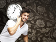 portrait of a handsome young man carrying a clock against a vint