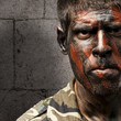 young soldier with camouflage paint looking very serious against