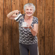 portrait of a vitality senior woman serving a tea cup against a
