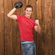 young man doing fitness with weights against a wooden wall young man doing fitness with weights against a wooden wall