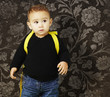 portrait of adorable kid carrying yellow backpack against a vint portrait of adorable kid carrying yellow backpack against a vint