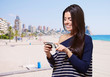 portrait of young woman touching a modern mobile against the bea