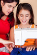 Hispanic mother and daughter sewing together