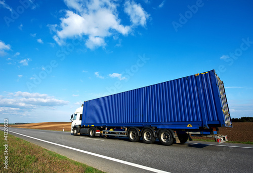 Photo: Red lorry with grey trailer over blue sky Red lorry with grey trailer over blue sky