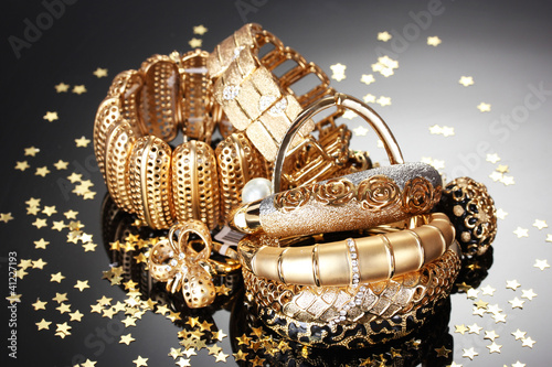 Photo: Beautiful golden jewelry on grey background Beautiful golden jewelry on grey background