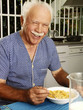 Abuelo desayunando cereal en casa.