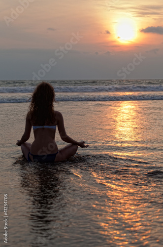 Photo: Silhouette of a beatiful woman meditating on a rock by the sea Silhouette of a beatiful woman meditating on a rock by the sea
