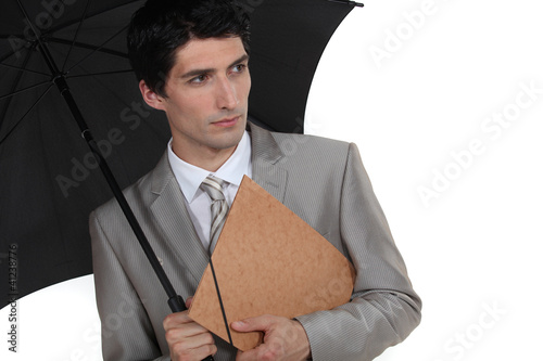 Photo: A businessman holding an umbrella. A businessman holding an umbrella.