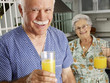 Abuelos bebiendo jugo de naranja en una cocina.