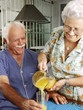 Abuelos bebiendo jugo de naranja en una cocina.