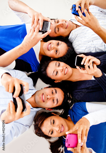 Photo: Young people texting on phones Young people texting on phones