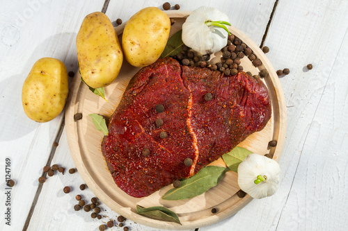 Photo: Raw steak spiced with herbs ready for baking Raw steak spiced with herbs ready for baking