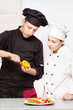 Foto: Senior chef teaches young chef to decorate fruit Senior chef teaches young chef to decorate fruit