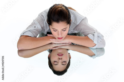Photo: Woman with her eyes closed leaning on a mirrored table Woman with her eyes closed leaning on a mirrored table