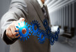 Photo: business man hand point cogs icons in board room business man hand point cogs icons in board room