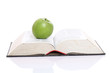 Green apple over a open book isolated on white