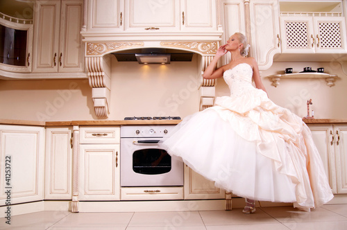 Photo: beautiful bride stands in the kitchen beautiful bride stands in the kitchen