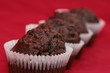 Four chocolate muffins in row over the red background Four chocolate muffins in row over the red background