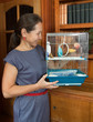 woman holding a cage with blue budgie