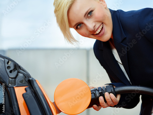 Photo: Business woman is loading electrically powered car outdoors Business woman is loading electrically powered car outdoors