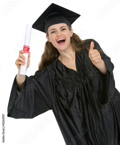 Photo: Happy graduation student girl with diploma showing thumbs up Happy graduation student girl with diploma showing thumbs up