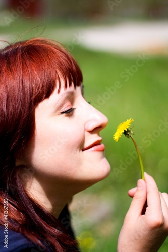 Photo: Girl blowing on white dandelion in the forest Girl blowing on white dandelion in the forest