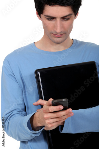 Photo: A casual young man with a laptop and a cellphone. A casual young man with a laptop and a cellphone.