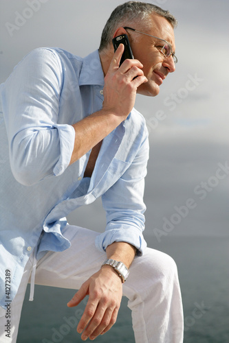Photo: Man admiring the coastal view whilst making a telephone call Man admiring the coastal view whilst making a telephone call