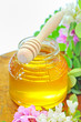 glass jar full of honey and stick with acacia pink and white  fl