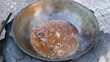 Kettle with cooking meat over burning campfire.