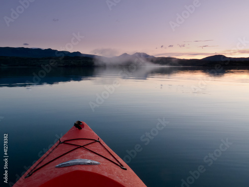 Photo: Paddling in a kayak through calm sunset waters Paddling in a kayak through calm sunset waters