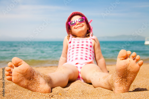 Photo: little girl lying on a sandy beach little girl lying on a sandy beach