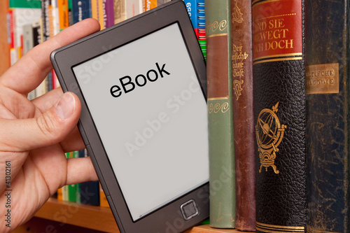 Foto: eBook vs Buch, e-Reader aus einem Bücherregal ziehen eBook vs Buch, e-Reader aus einem Bücherregal ziehen