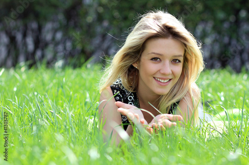 Photo: Cute young female lying on grass field at the park Cute young female lying on grass field at the park