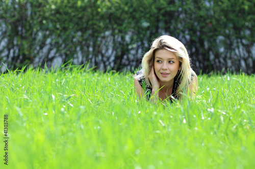 Photo: Cute young female lying on grass field at the park Cute young female lying on grass field at the park