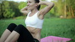 Woman in sport outfit doing sit ups in a park