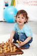 Adorable little boy playing with chess pieces