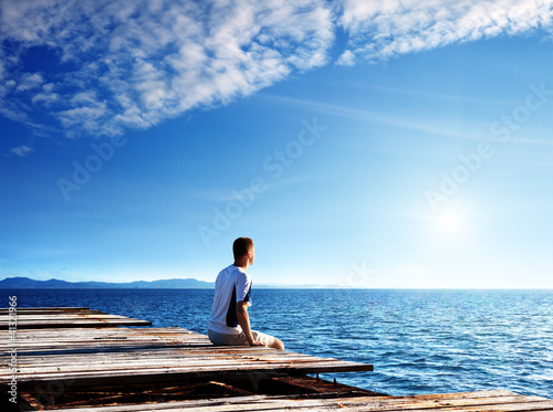 Photo: young man relax siting on pier young man relax siting on pier