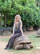 tourist woman riding  on giant turtle in La Vanille Reserve park