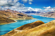 Bright blue lake winds through Himalayas in Tibet on sunny day