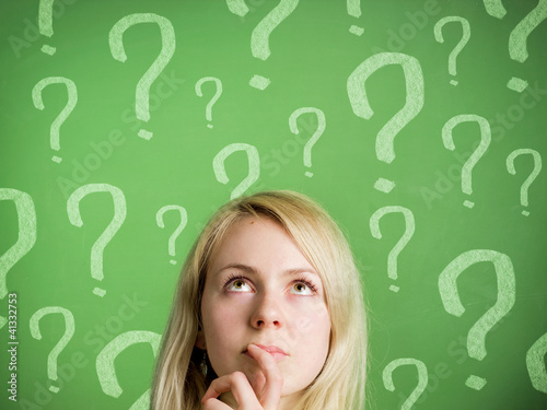 Photo: Thinking woman in front of blackboard with question marks Thinking woman in front of blackboard with question marks