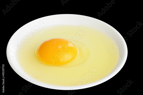 Photo: Egg in a white plate on black background Egg in a white plate on black background
