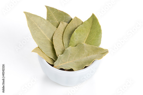Photo: Bay Leaves in a white bowl on white background. Bay Leaves in a white bowl on white background.