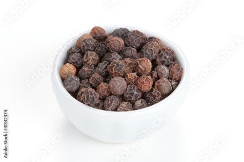 Photo: Black pepper (Piper nigrum) in a white bowl on white background. Black pepper (Piper nigrum) in a white bowl on white background.