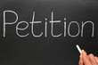 Writing Petition with white chalk on a blackboard.
