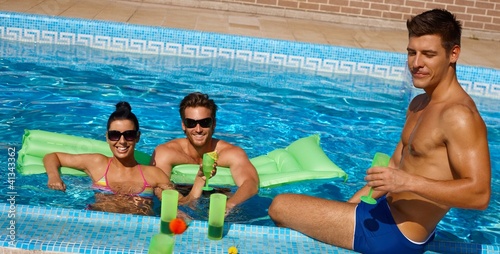 Photo: Young friends in swimming pool smiling Young friends in swimming pool smiling