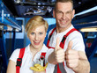 Master mechanic and apprentice show thumbs up in a garage