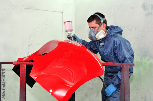 Photo: Man painting a red fender. Man painting a red fender.