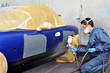 Worker painting a blue car.