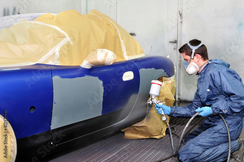 Photo: Worker painting a blue car. Worker painting a blue car.